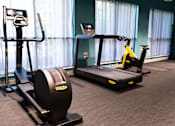 Thumbnail 7 of 23 - A gym with a treadmill, elliptical trainer and a stationary bike.