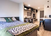Thumbnail 1 of 23 - A bedroom with a bed, desk, and chair.