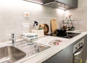 Thumbnail 19 of 23 - A kitchen with a stainless steel sink and a stove top.