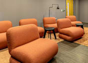 Thumbnail 36 of 36 - A row of orange chairs with black stools in front of them.