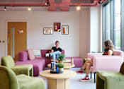 Thumbnail 8 of 36 - A man and a woman are sitting in a brightly colored waiting area.