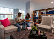 Thumbnail 10 of 51 - Two people sitting on a couch reading a book in a living room.
