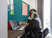 Thumbnail 45 of 51 - A woman with a scarf on her head is working on a laptop.