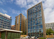 Thumbnail 50 of 51 - A modern building with a glass facade stands tall in an urban setting.