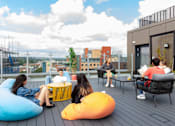 Thumbnail 45 of 51 - A group of people are sitting on a rooftop terrace.