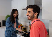 Thumbnail 18 of 51 - A man and a woman are cooking together in a modern kitchen.
