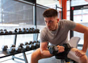 Thumbnail 10 of 51 - A man is working out with dumbbells in a gym.
