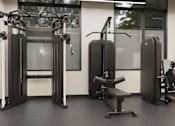 Thumbnail 30 of 34 - A gym with a variety of equipment including a squat rack, a leg press machine, and a bench.