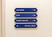 Thumbnail 49 of 56 - A sign with four directions to Laundry, Gym, Games Room and Social Area.