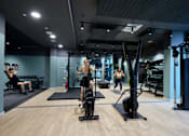Thumbnail 12 of 73 - A gym with people exercising and fitness equipment.