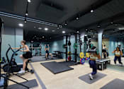 Thumbnail 9 of 73 - A gym with people exercising and a woman on an exercise bike.