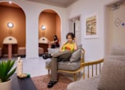Thumbnail 53 of 73 - A woman is sitting on a chair with headphones on.