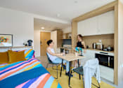 Thumbnail 22 of 73 - Two people are sitting at a table in a colorful room.