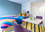 Thumbnail 14 of 56 - A bedroom with a colorful bedspread and a purple chair.