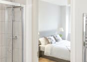Thumbnail 19 of 22 - a bedroom with a bed and a glass shower