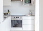 Thumbnail 2 of 11 - a white kitchen with a table and a glass of orange juice