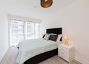 Thumbnail 15 of 16 - a bedroom with a bed and a large window