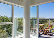 Thumbnail 1 of 16 - a room with large windows and a table and chairs on a balcony