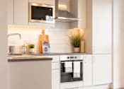 Thumbnail 7 of 10 - a white kitchen with stainless steel appliances and a wood floor