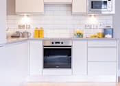 Thumbnail 7 of 15 - a white kitchen with a stove and a microwave