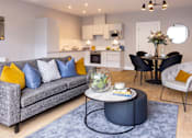 Thumbnail 9 of 15 - a living room with a couch and a table in front of a kitchen