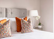 Thumbnail 14 of 15 - a bed with pillows and a nightstand with a lamp and a plant