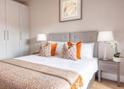 Thumbnail 1 of 15 - a bedroom with a white bed and orange pillows