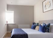 Thumbnail 10 of 15 - a bedroom with a bed with blue pillows and a window