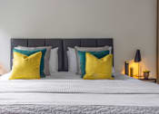 Thumbnail 8 of 23 - a bedroom with a bed with yellow pillows and white bedding