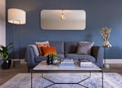 Thumbnail 14 of 23 - a living room with a gray couch and a coffee table