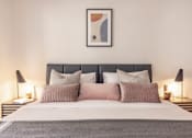 Thumbnail 11 of 23 - a bedroom with a bed with pillows and a painting on the wall