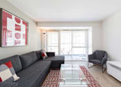 Thumbnail 6 of 16 - a living room with a gray couch and a glass table  and a large window