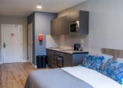 Thumbnail 7 of 8 - a bedroom with a bed and a kitchen with a sink