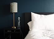 Thumbnail 12 of 14 - a bedroom with blue walls and a bed with a white pillow and a nightstand
