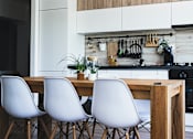 Thumbnail 4 of 14 - a kitchen with white cabinets and a wooden table and chairs