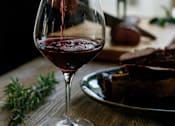 Thumbnail 13 of 20 - a person pouring red wine into a wine glass on a table