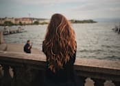 Thumbnail 7 of 20 - a woman sitting on a ledge by the water