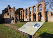 Thumbnail 10 of 12 - an interpretive sign stands in front of the ruins of the aqueduct