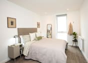 Thumbnail 22 of 23 - A bedroom with a large bed and a small table with a lamp.