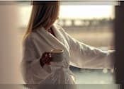 Thumbnail 8 of 25 - A woman in a white robe is holding a cup.
