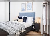 Thumbnail 4 of 25 - A bed with a blue headboard and a grey and white blanket is in the image.