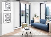 Thumbnail 3 of 25 - A living room with a blue couch, a coffee table, and a view of the city.