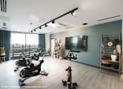 Thumbnail 9 of 30 - a gym with exercise bikes and a tv on the wall at Vox Apartments, Manchester