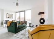 Thumbnail 10 of 30 - a living room with a green couch and a large window at Vox Apartments, Manchester
