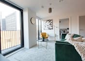 Thumbnail 13 of 30 - a living room with a green couch and a large window at Vox Apartments, Manchester