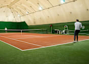 Thumbnail 2 of 4 - A man is playing tennis on a court with a green wall in the background.