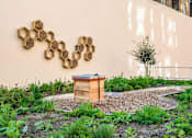 Thumbnail 4 of 24 - A beehive sits in front of a wall with a honeycomb pattern.