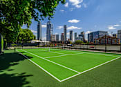 Thumbnail 5 of 24 - A tennis court with a city skyline in the background.