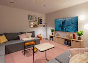 Thumbnail 8 of 27 - a living room with a gray couch and a television