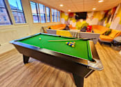 Thumbnail 4 of 11 - a game room with a pool table and orange couches
